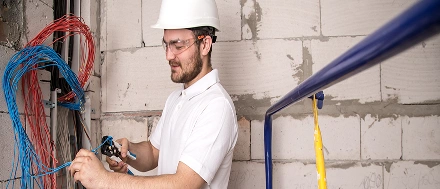 Elektricien die elektrische bedrading aanlegt op een onafgewerkte muur op een bouwplaats.